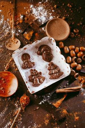Christmas chocolate figures Santa Claus, Christmas tree, bells, candle are on the dark table next to...
