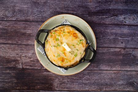 Classic French onion soup with grated cheese and parsley.on the background of a wooden table