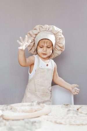 Portrait of a little cook kneading dough in an apron and a chef's hat. Cooking children's lifestyle...