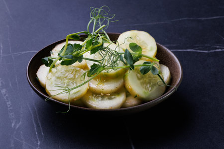 Fresh Cucumber Salad With Microgreens In A Dark Brown Bowlの写真素材