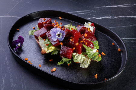Beet Salad on Crisp Greens with Edible Flowers Arranged on a Dark Plate,Artful Presentationの写真素材