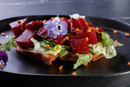 Beet Salad on Crisp Greens with Edible Flowers Arranged on a Dark Plate,Artful Presentationの写真素材