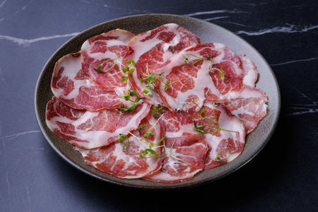 plate with sliced cured meat, pork neck, prosciutto coppa, Italian delicacy,の写真素材