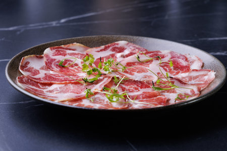plate with sliced cured meat, pork neck, prosciutto coppa, Italian delicacy,の写真素材