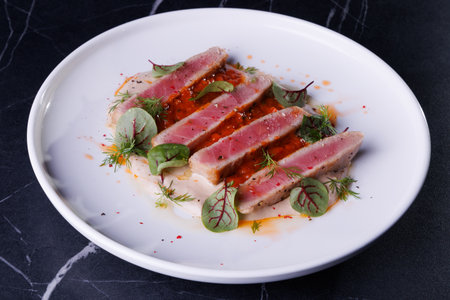 Seared Tuna Steak Slices on Creamy Sauce with Fresh Greens and Herbsの写真素材