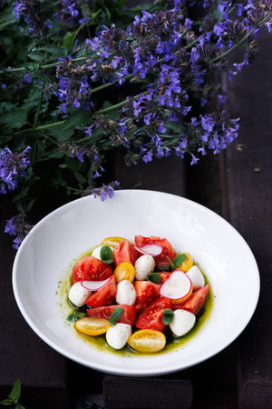 Bright Tomato Burrata Salad With Radish Slices and Olive Oil Drizzle on White Plate Garnished