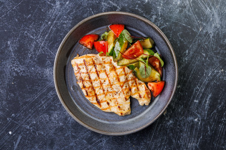 Grilled Chicken With Fresh Tomato Cucumber Salad On a Dark Ceramic Plateの写真素材