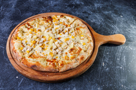 Delicious Cheese Pizza With Chicken, Pineapple, and Corn On a Round Wooden Boardの写真素材