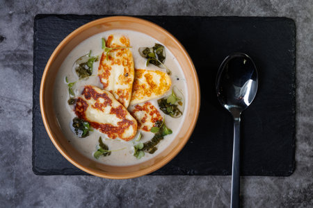 Creamy Cheese Soup in Teal Bowl on Slate, Garnished with Herbs and Melted Cheese