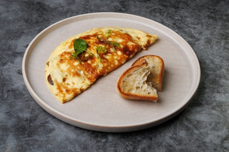 A warm breakfast setting featuring a golden cheese omelette garnished with greens, a slice of crusty...