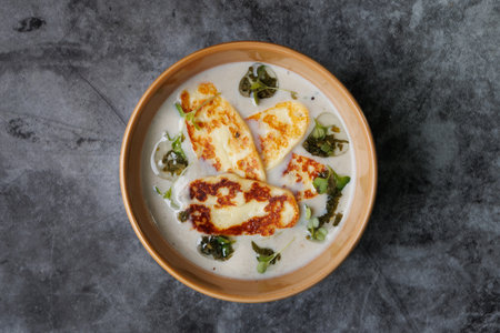 Creamy Cheese Soup in Teal Bowl, Garnished with Herbs and Melted Cheeseの写真素材