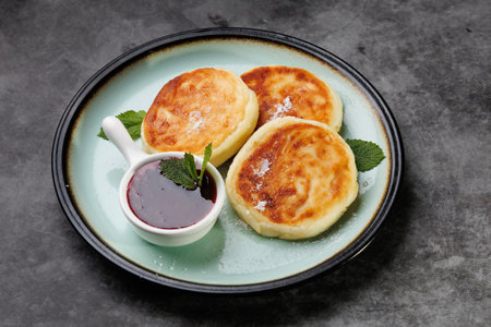 Golden-crusted pancakes served on a white plate with berry sauce and fresh mint create a warm and cozy atmosphere for breakfast or dessert, perfect for cooking, cafes, and home cooking.の写真素材
