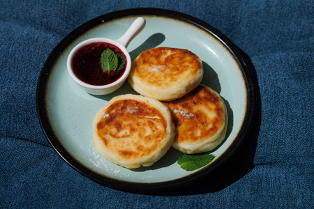 Golden-crusted pancakes served on a white plate with berry sauce and fresh mint create a warm and...
