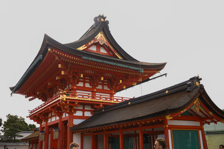 vivid Japanese temple complex featuring red wooden structures, ornate curved roofs, and a stone lantern. Bright sky and cultural architecture convey heritage, spirituality, and travel allure.の写真素材