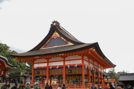 vivid Japanese temple complex featuring red wooden structures, ornate curved roofs, and a stone lantern. Bright sky and cultural architecture convey heritage, spirituality, and travel allure.の写真素材