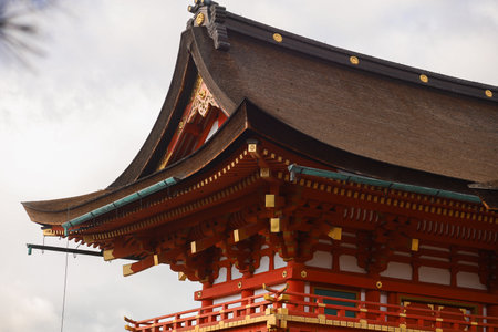 A close view of a traditional Japanese temple roof featuring curved eaves, red wooden beams, and gold accents. Ideal for culture, heritage, travel, and architecture themes.の写真素材