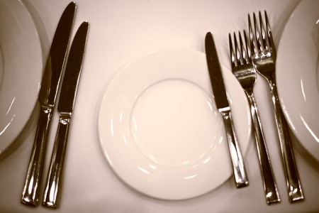 plates napkins forks knives on a white tableclothの写真素材