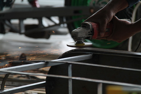 worker sawing metal with a grinder, sparks flyの写真素材