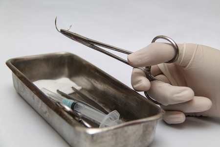 Holding a surgery needle (straight 1/2 circle) with needle holder and hand glovesの写真素材