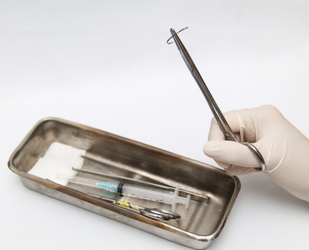 Holding a surgery needle (straight 1/2 circle) with needle holder and hand glovesの写真素材