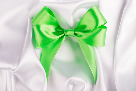 Green ribbon satin bow on the nice white silkの写真素材