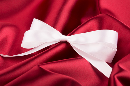 White ribbon satin bow on the nice red silkの写真素材