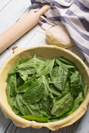 Raw spinach pie on the blue wooden backgroundの写真素材