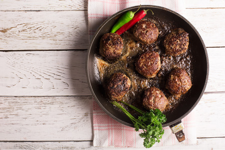 Fried meatballs on the pan with vegetables and herbsの写真素材