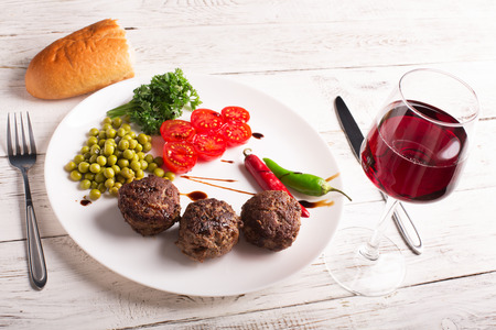 Fried meatballs on the plate and wine on the wooden tableの写真素材