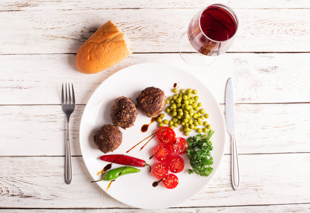 Fried meatballs on the plate and wine on the wooden tableの写真素材