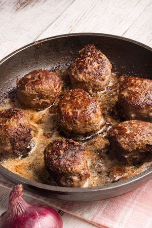 Fried meatballs on the pan and vegetables on the wooden tableの写真素材