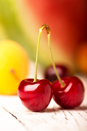 Two cherries an other fruits on a wooden tableの写真素材