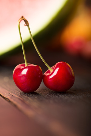 Two cherries an other fruits on a black wooden tableの写真素材