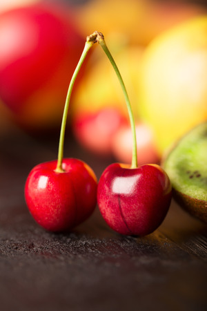Two cherries an other fruits on a wooden tableの写真素材