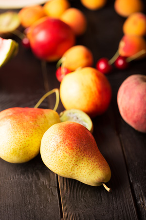 Tasty pears and other fruits on a wooden tableの写真素材