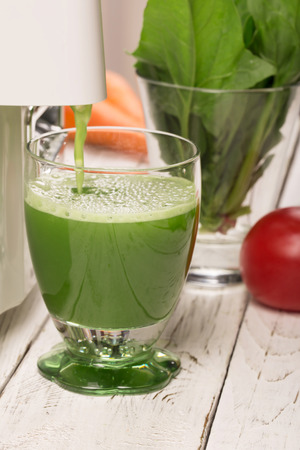 Spinach juice from juicers pouring into a glassの写真素材