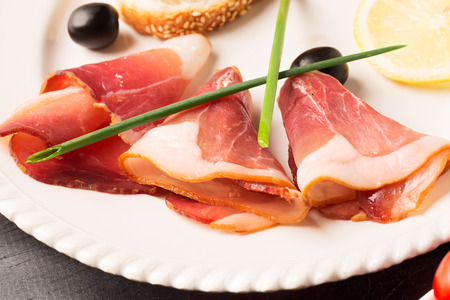 Sliced tasty spanish jamon and vegetables on a plateの写真素材