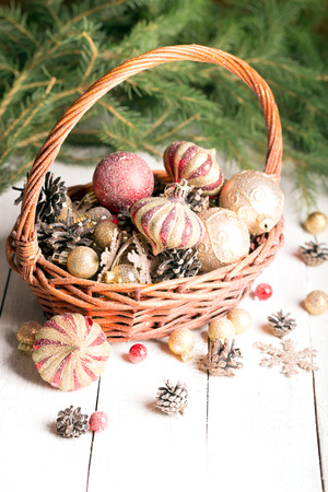 Christmas basket with red and golden ornaments, fir-cones on a wooden tableの写真素材