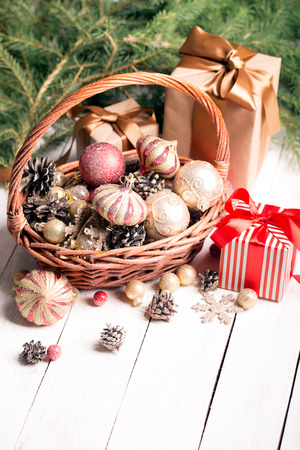 Christmas basket with red and golden ornaments, fir-cones on a wooden tableの写真素材