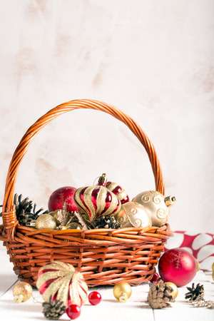 Christmas basket with red and golden ornaments, fir-cones on a wooden tableの写真素材