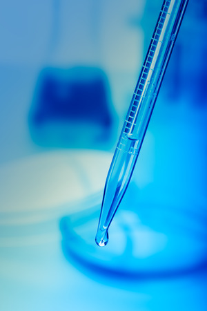 Pipette with drop of water and lab equipmentの写真素材