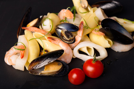 Pasta conchiglioni with seafood on the black stone plateの写真素材