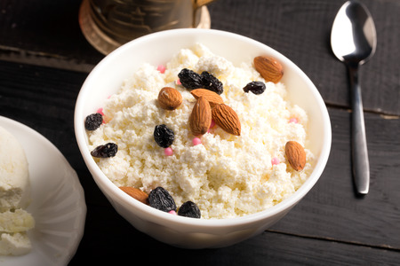 Cottage cheese with almond and raisins in a white bowlの写真素材