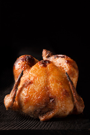 Whole roasted chicken on the black wooden table. Dark backgroundの写真素材
