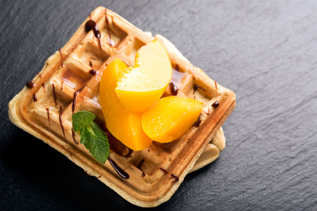 Viennese waffles with peaches and chocolate, decorated with mintの写真素材