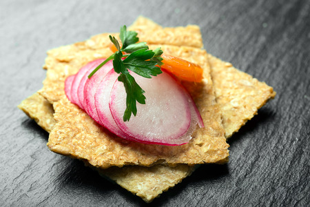 Snack with radish, parsley on cereals. Black backgroundの写真素材