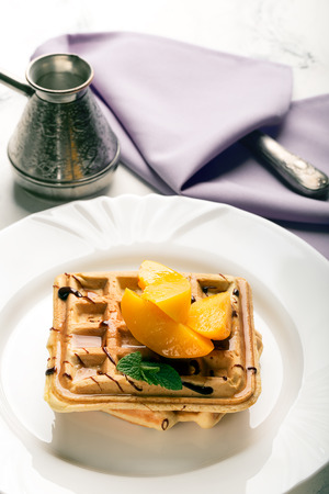 Viennese waffles with peaches and chocolate, decorated with mintの写真素材