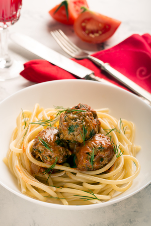 Meat balls in tomato sauce with pasta on a white backgroundの写真素材