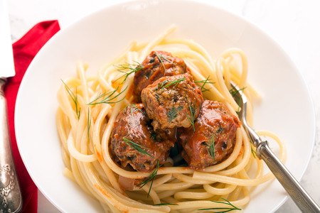 Meat balls in tomato sauce with pasta on a white backgroundの写真素材