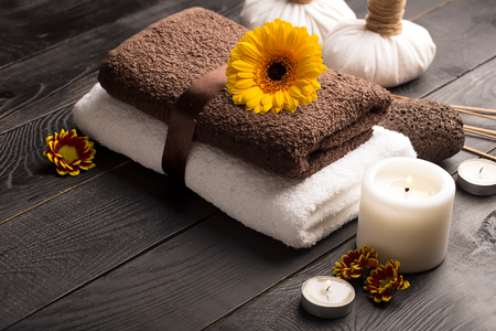SPA still life with towel, candles and gerbera flowers on a black wooden surfaceの写真素材